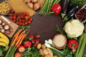 Photo of a table top full of fresh vegetables, fruit, and other healthy foods