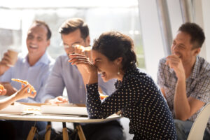 Office Meal Service DC- woman laughing at lunch meeting with three men